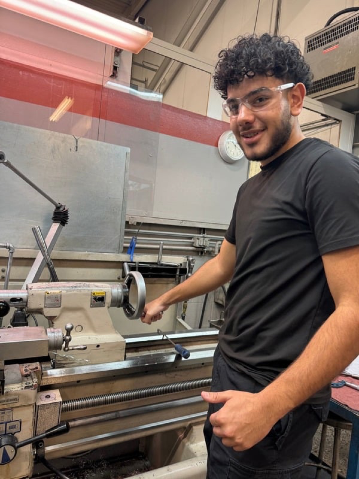Michael working at a metal lathe in the machine shop